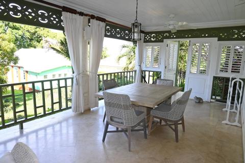 This image depicts an elegant outdoor dining area on a covered porch or veranda