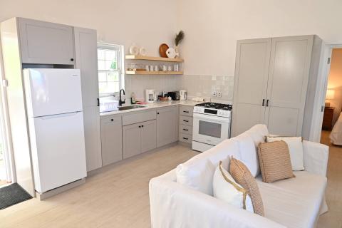The image shows a modern, compact kitchen and a part of a living area