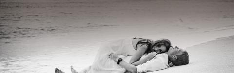 This image captures a peaceful and romantic moment of a couple lying on the beach