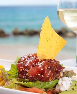 The image shows a dish that appears to be a tuna tartare served on a bed of lettuce with various accompaniments such as diced tomatoes