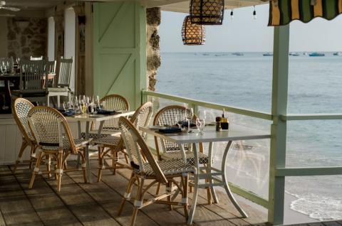 The image shows a seaside dining area, likely part of a restaurant