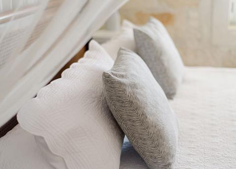 The image features a collection of pillows arranged on a bed or a couch