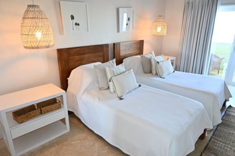 The image shows a modern and well-lit bedroom with two single beds