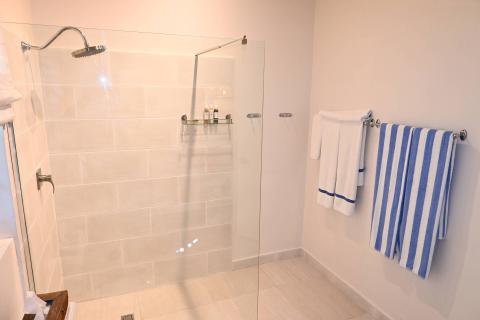 This image shows a modern bathroom, specifically focusing on a glass-doored shower area