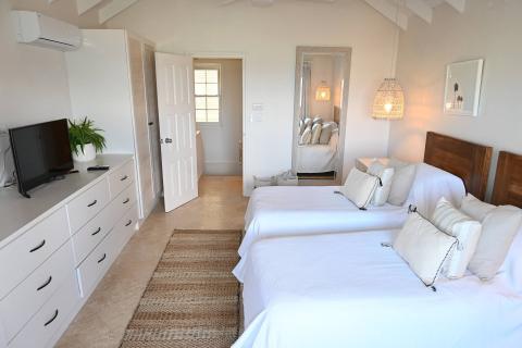 This image shows a neatly organized bedroom with a coastal or minimalist decor style