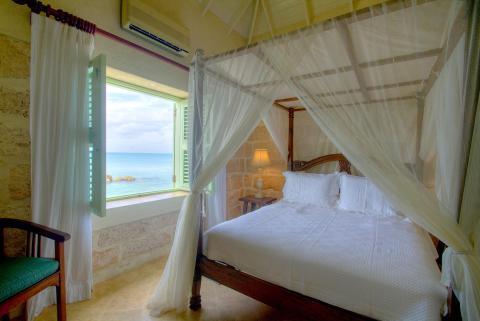 This image shows a beautifully arranged bedroom with a coastal view