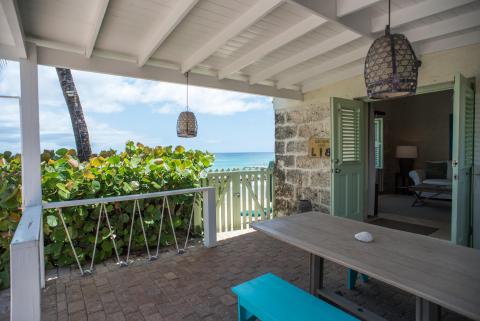 The image shows a pleasant, inviting beach house porch looking out to the sea