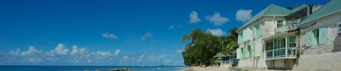 This image depicts a serene coastal scene with a clear blue sky dotted with fluffy white clouds