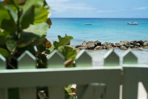 This image features a beautiful coastal scene viewed from behind a white picket fence