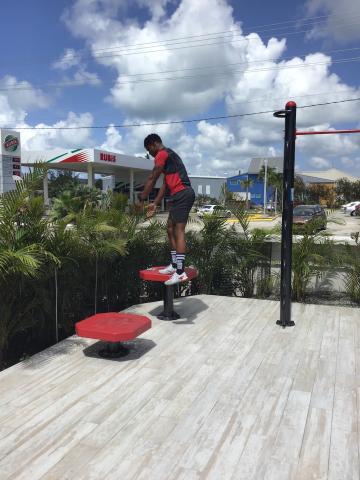 The image shows an outdoor scene where a person is standing on a set of red and black fitness or agility training step platforms