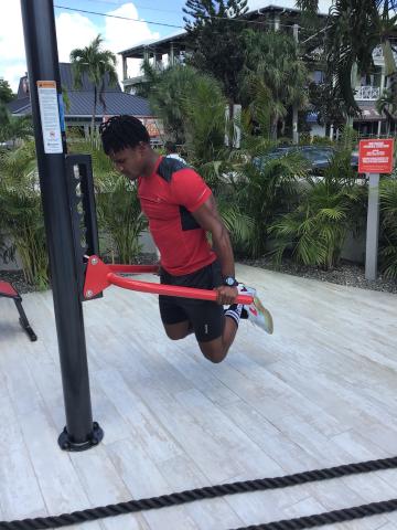 The image shows a person using outdoor fitness equipment at a public exercise area