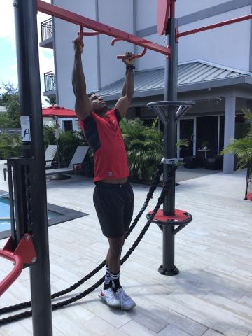 In this image, there is a man exercising at an outdoor gym area