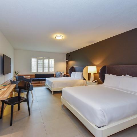 The image displays a neatly arranged hotel room with a contemporary design