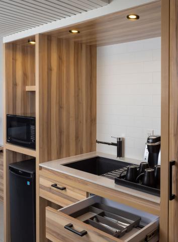This image shows a modern, compact kitchen setup mostly built into a wooden cabinetry