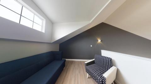 This image shows a modernly designed interior space featuring an attic room with a slanted ceiling