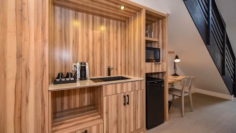 This image shows a compact and stylish kitchenette with wood paneling