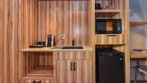 This image shows a compact, modern kitchenette set against a backdrop of wood-paneled walls