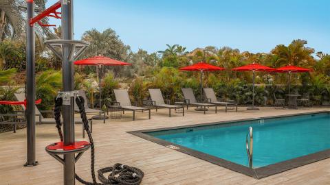 This image shows an outdoor setting featuring a beautiful swimming pool area surrounded by lush tropical vegetation