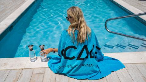 This image features a woman sitting by a swimming pool