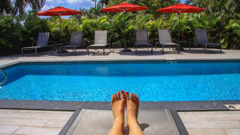 The image shows a bright and sunny day at a luxurious pool area