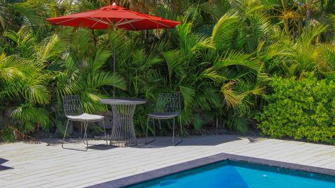 This image features a relaxing outdoor patio area adjacent to a swimming pool