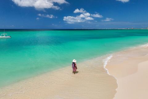 This image shows a beautiful beach scene with clear turquoise waters and a white sandy shoreline