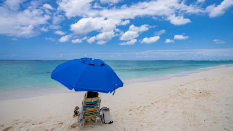 The image shows a beautiful beach scene with clear blue skies and white fluffy clouds overhead