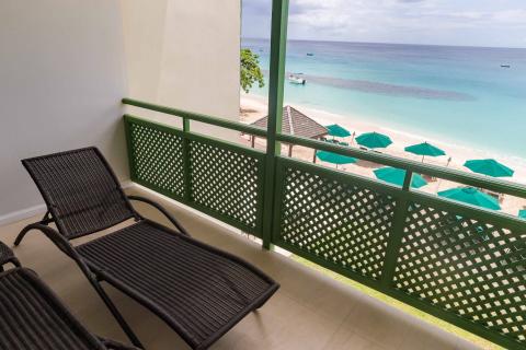 The image shows a balcony with a picturesque view of a beach