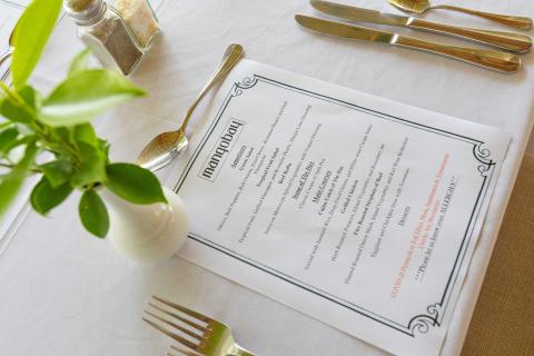 The image shows a nicely set restaurant table with a menu and some tableware