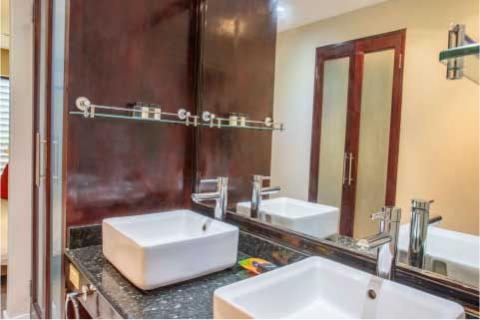 The image shows a modern bathroom interior featuring a dark granite countertop with two rectangular vessel sinks