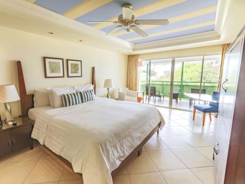 This image depicts a spacious and well-lit hotel or resort bedroom