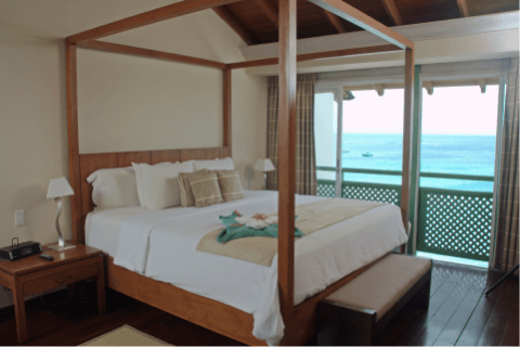 The image shows a stylish bedroom in a tropical or beachfront location