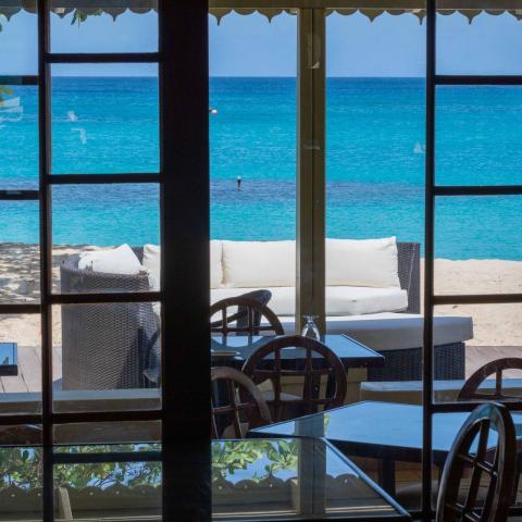 The image shows a view from inside a building looking out towards a beautiful beach scene