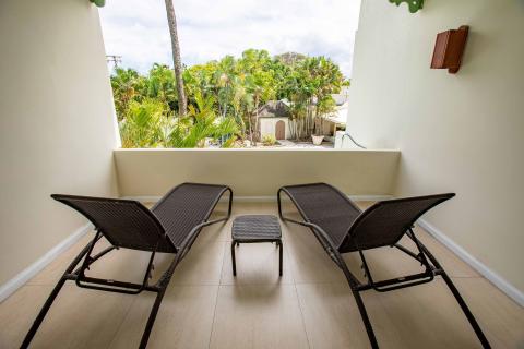 The image shows a balcony with a view of lush greenery