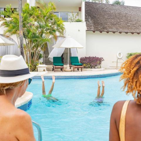 The image shows a serene poolside scene at a luxurious resort