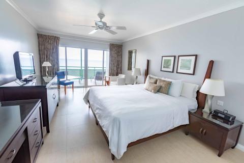 This image shows a well-furnished hotel room with a scenic ocean view