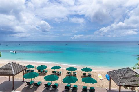 This image captures a picturesque beach setting with a clear, aqua-blue ocean framed by white sandy shores