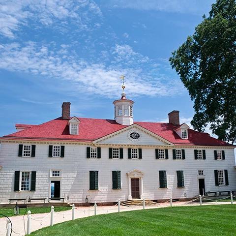 This image shows a large historic mansion with a red-tiled roof and white walls