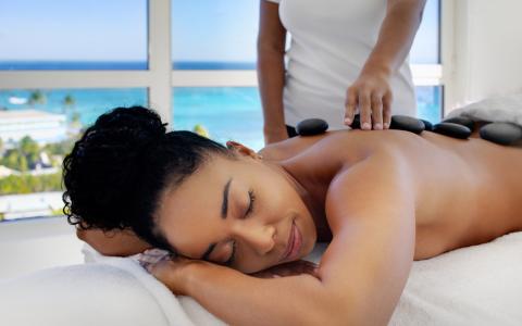 The image depicts a serene hot stone massage session