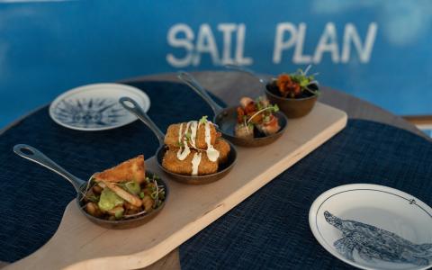 This image shows an assortment of appetizers served on an attractive, wooden paddle board