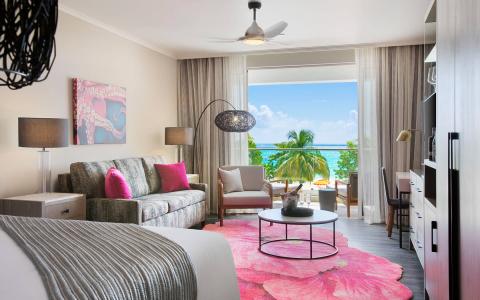 This image shows a well-decorated modern hotel room with an ocean view