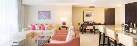 The image depicts a well-appointed, modern living room that flows into a dining area