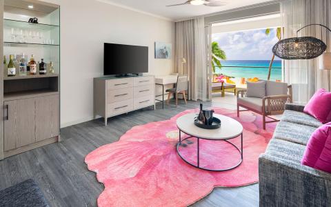 This image displays a stylish and modern beachfront hotel room with an interior design that emphasizes comfort and luxury