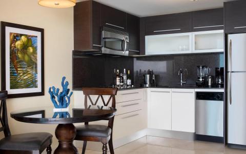The image depicts a modern kitchen and a small dining area