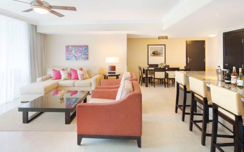 This image depicts a well-decorated, modern living room that extends into a dining area and a kitchen bar