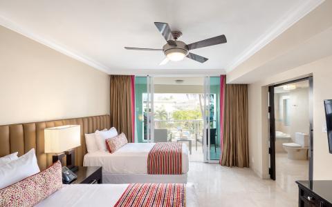 The image shows a well-lit, modern hotel room with a tropical view