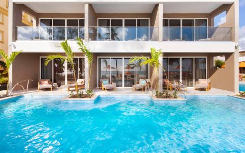 This image shows a luxurious outdoor pool area in front of a modern hotel or resort