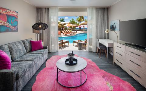 This image shows a modern and elegantly decorated living room with a view of a pool area