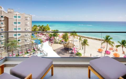 This image shows a view from a balcony overlooking a luxurious beachside resort