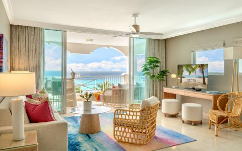 This image showcases a beautifully appointed modern living room that opens up to a scenic ocean view